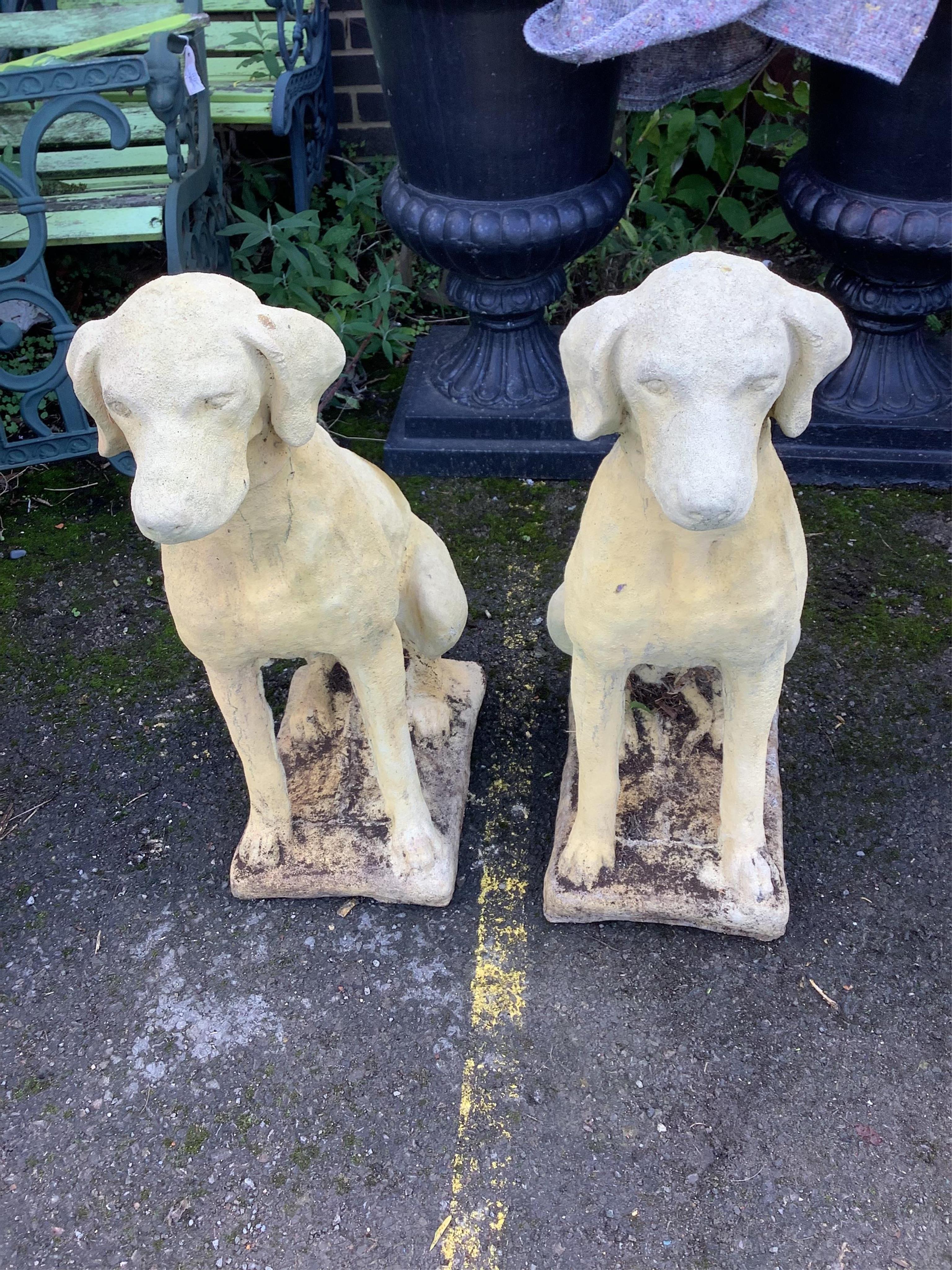 A pair of reconstituted stone models of seated hounds, height 70cm. Condition - fairly heavily weathered